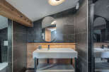 This modern bathroom boasts a sleek design with dark tiled walls and a stylish vanity.