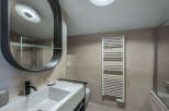 This modern bathroom features a sleek design with a large oval mirror and a stylish sink.
