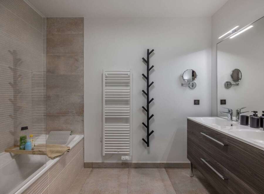 This modern bathroom features a sleek design with a bathtub, a stylish vanity, and a large mirror.