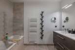 This modern bathroom features a sleek design with a bathtub, a stylish vanity, and a large mirror.