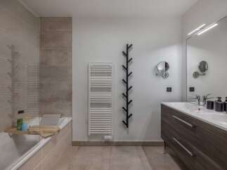 This modern bathroom features a sleek design with a bathtub, a stylish vanity, and a large mirror.