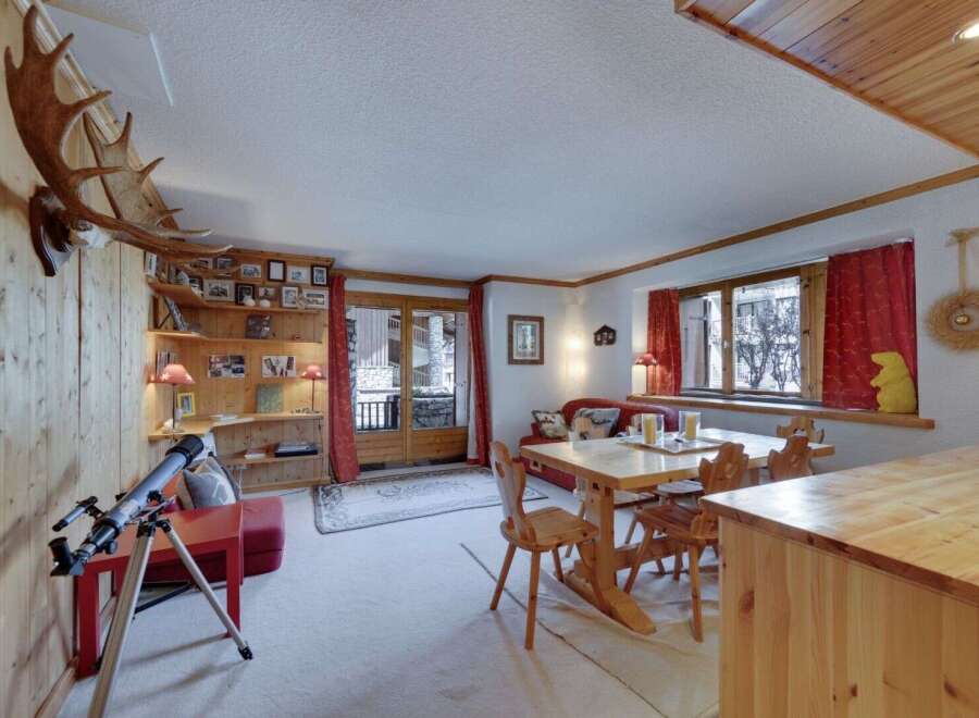 Step into this charming chalet, boasting a cozy living space with a rustic dining area and a comfortable seating arrangement.