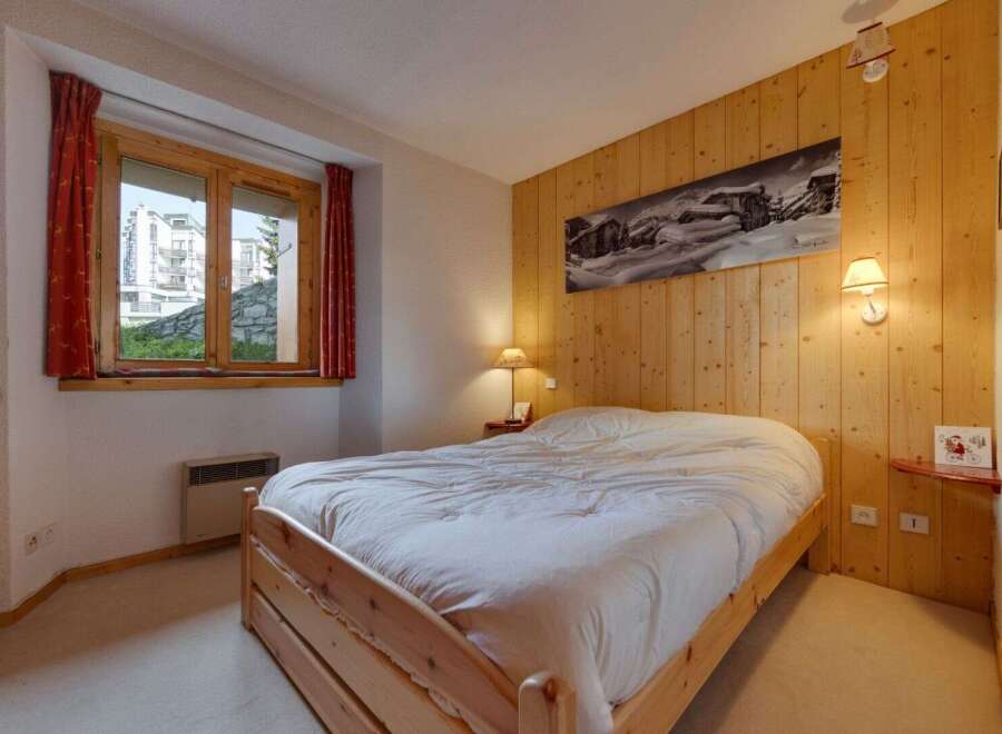 Cozy bedroom featuring a wooden bed frame and a warm wooden wall paneling.