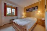 Cozy bedroom featuring a wooden bed frame and a warm wooden wall paneling.