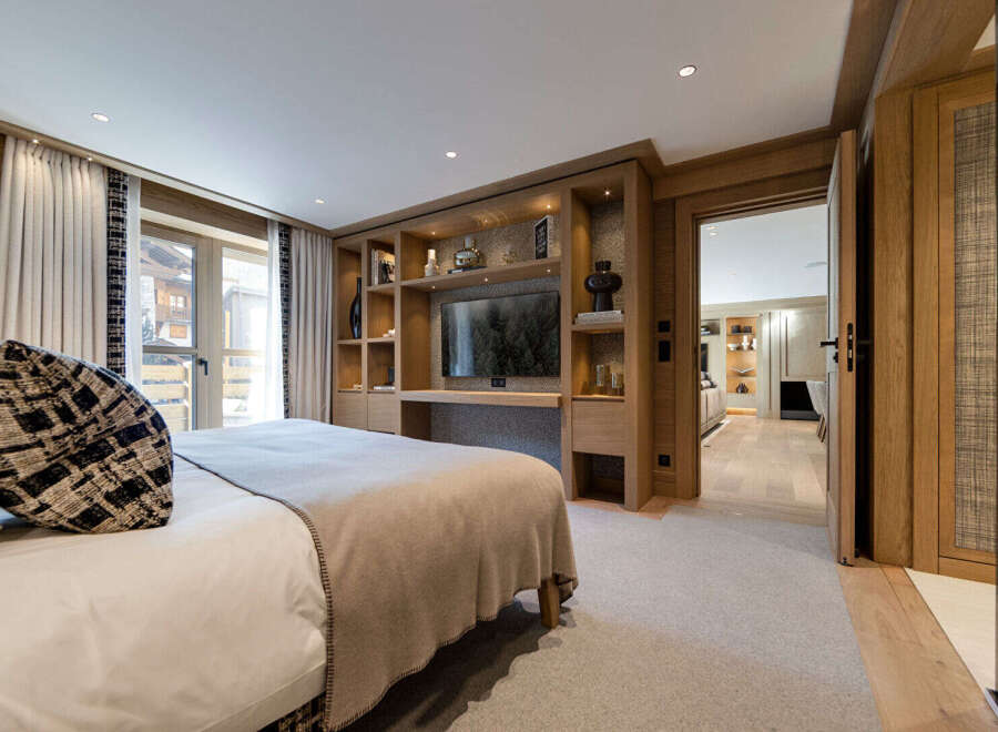 Experience luxury living in this stunning bedroom, featuring a custom-built entertainment center with a large-screen TV and ample storage.