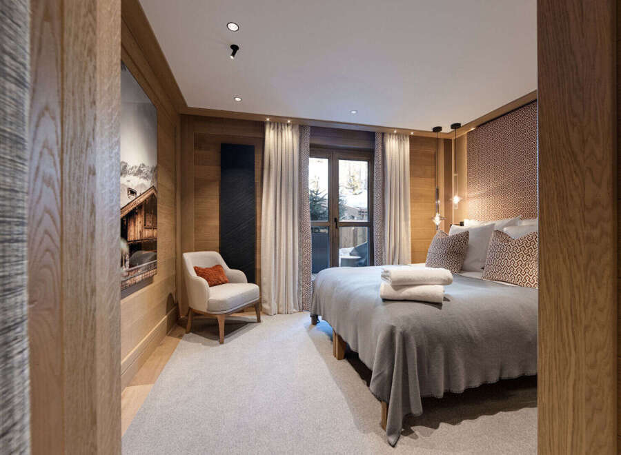 Experience luxury living in this stunning bedroom featuring exquisite wooden paneling and a cozy armchair.