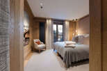 Experience luxury living in this stunning bedroom featuring exquisite wooden paneling and a cozy armchair.