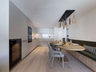 This modern kitchen and dining area features sleek, minimalist design with high-end appliances and custom cabinetry.