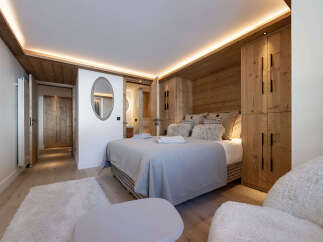 Experience luxury in this stunning bedroom featuring a cozy bed, plush pillows, and elegant wooden accents.