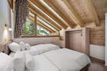 This cozy bedroom features a unique sloped ceiling with exposed wooden beams, creating a warm and inviting atmosphere.