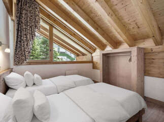 This cozy bedroom features a unique sloped ceiling with exposed wooden beams, creating a warm and inviting atmosphere.