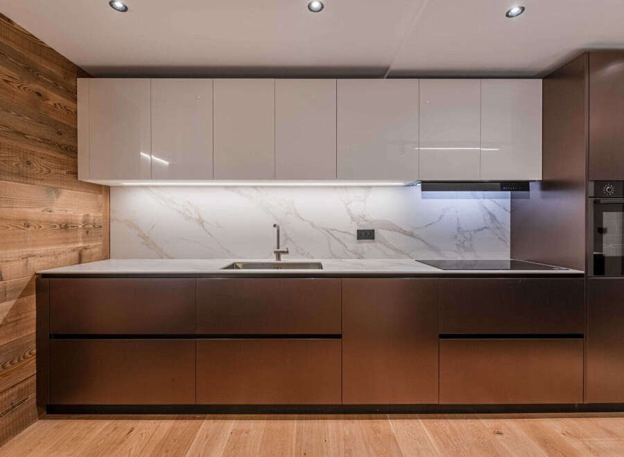 This modern kitchen boasts sleek, high-gloss cabinets and a stunning marble backsplash, creating a sophisticated and inviting atmosphere.