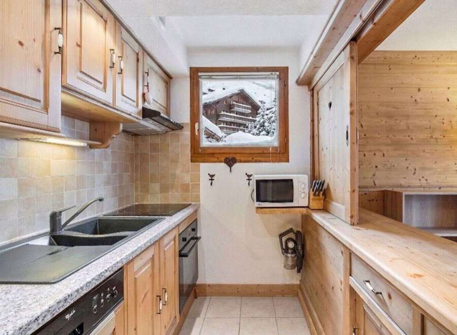 This charming kitchen features warm wooden cabinetry and a granite countertop, creating a cozy and inviting atmosphere.