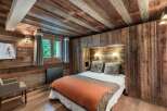 This cozy bedroom showcases rustic charm with its wooden walls and ceiling, creating a warm and inviting atmosphere.
