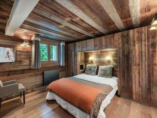 This cozy bedroom showcases rustic charm with its wooden walls and ceiling, creating a warm and inviting atmosphere.