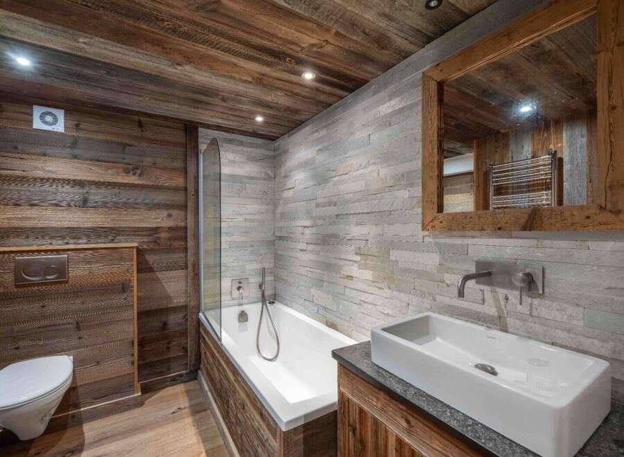 This stunning bathroom showcases a rustic design with wood paneling and stone walls, creating a warm and inviting atmosphere.