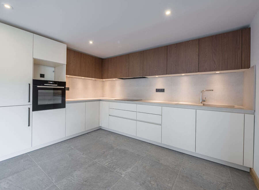 This modern kitchen boasts sleek, white cabinetry complemented by warm wood accents, creating a stylish and inviting space.