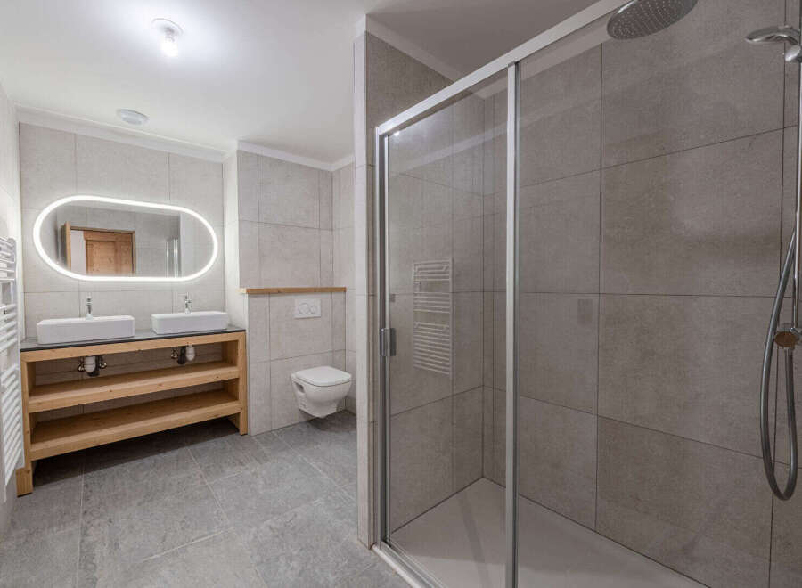 Step into this modern bathroom, featuring a sleek glass shower enclosure and stylish tiled walls.