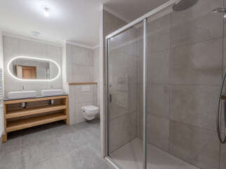 Step into this modern bathroom, featuring a sleek glass shower enclosure and stylish tiled walls.
