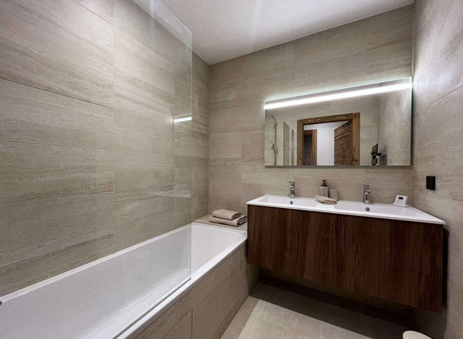 This modern bathroom features a sleek design with a spacious bathtub and a stylish vanity.