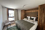Experience luxury living in this stunning bedroom featuring a cozy bed with stylish pillows and a warm, inviting wooden headboard.