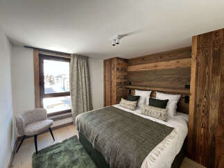 Experience luxury living in this stunning bedroom featuring a cozy bed with stylish pillows and a warm, inviting wooden headboard.