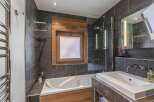 This modern bathroom features a sleek design with dark gray tiles and wooden accents.