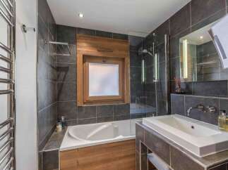 This modern bathroom features a sleek design with dark gray tiles and wooden accents.