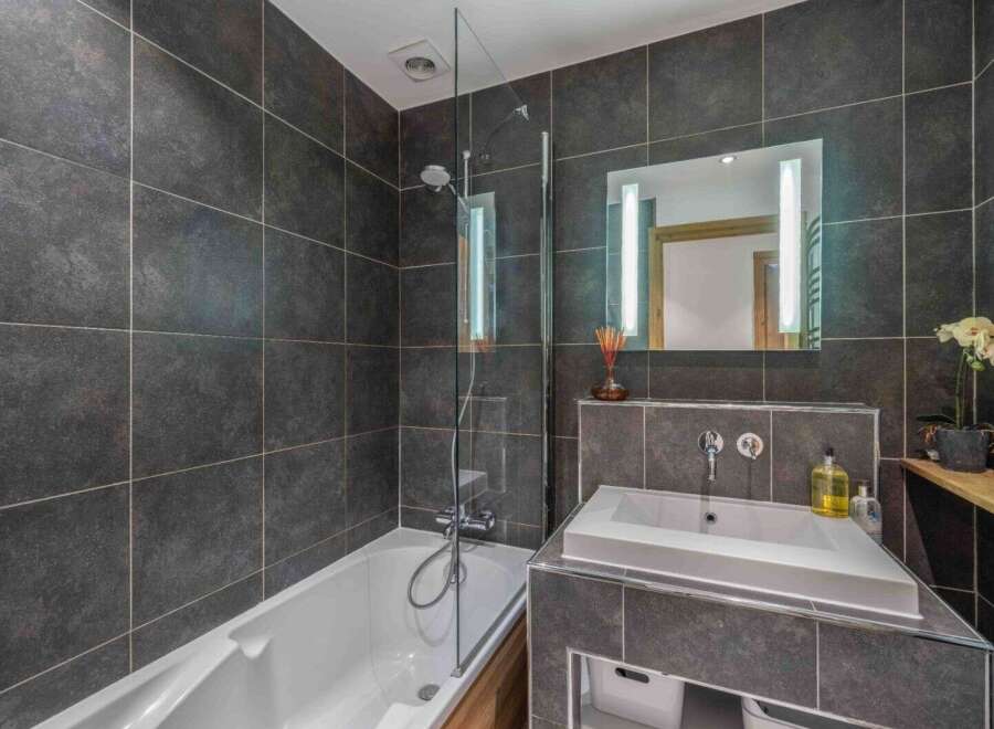 This modern bathroom features sleek dark gray tiles, creating a sophisticated and contemporary ambiance.