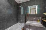 This modern bathroom features sleek dark gray tiles, creating a sophisticated and contemporary ambiance.