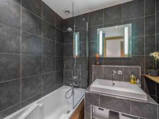 This modern bathroom features sleek dark gray tiles, creating a sophisticated and contemporary ambiance.