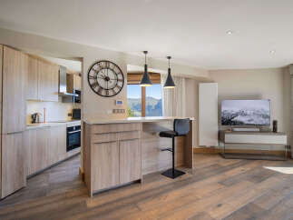 Experience modern living in this open-concept space featuring a sleek kitchen with light wood cabinetry and integrated appliances.