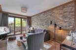 Experience luxury living in this stunning property, featuring a cozy living room with a stone wall and a plush rug.