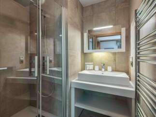 Step into a modern bathroom oasis! This stunning space features a sleek shower enclosure, a stylish vanity with a contemporary sink, and a convenient towel warmer.