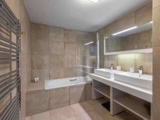 This modern bathroom features a sleek design with a double vanity and a luxurious bathtub.