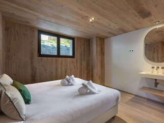 This stunning bedroom features a warm and inviting ambiance with its wooden walls and ceiling.
