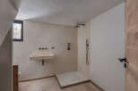 This modern bathroom features a sleek, minimalist design with a stone sink and a walk-in shower.