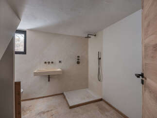 This modern bathroom features a sleek, minimalist design with a stone sink and a walk-in shower.