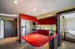 This modern kitchen boasts sleek red cabinetry and stainless steel appliances, creating a stylish and functional space.