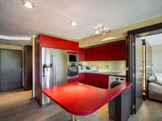This modern kitchen boasts sleek red cabinetry and stainless steel appliances, creating a stylish and functional space.