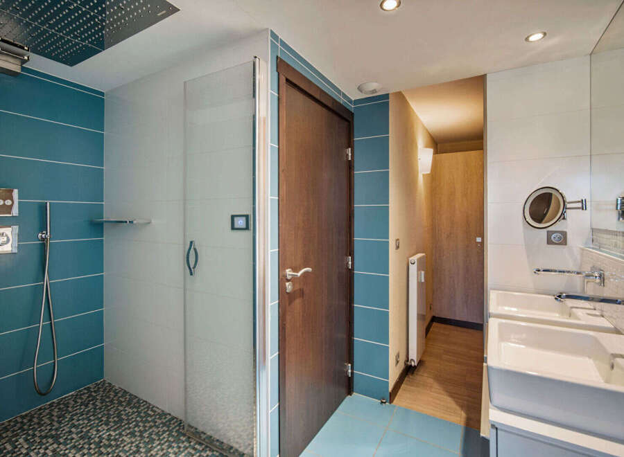 Step into a modern bathroom oasis! This stunning space boasts a sleek shower with a rainfall showerhead, complemented by stylish blue and white tilework.