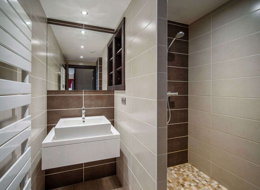 This modern bathroom features a sleek design with a floating sink and a walk-in shower.