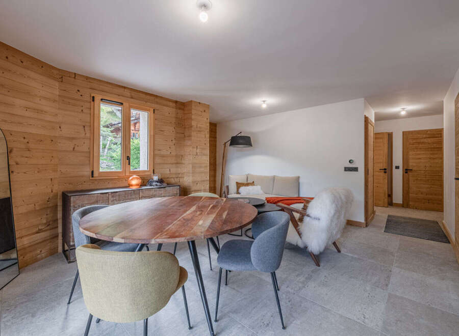 Experience the warmth and charm of this inviting living space, featuring a stunning wooden accent wall and a cozy dining area.