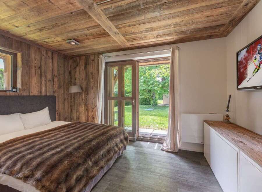 Experience rustic charm in this cozy bedroom featuring a wooden ceiling and walls, creating a warm and inviting atmosphere.