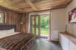 Experience rustic charm in this cozy bedroom featuring a wooden ceiling and walls, creating a warm and inviting atmosphere.