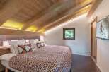 Experience the charm of this cozy bedroom featuring a stunning wooden ceiling and a comfortable bed with patterned bedding.