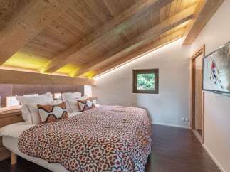 Experience the charm of this cozy bedroom featuring a stunning wooden ceiling and a comfortable bed with patterned bedding.