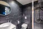 This modern bathroom features sleek black marble tiles, creating a luxurious and sophisticated ambiance.