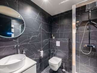 This modern bathroom features sleek black marble tiles, creating a luxurious and sophisticated ambiance.