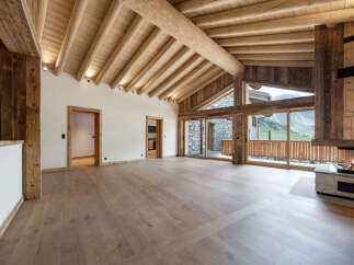 Experience luxurious mountain living in this stunning chalet featuring a grand open-plan living area with a magnificent stone fireplace and soaring wooden beamed ceilings.